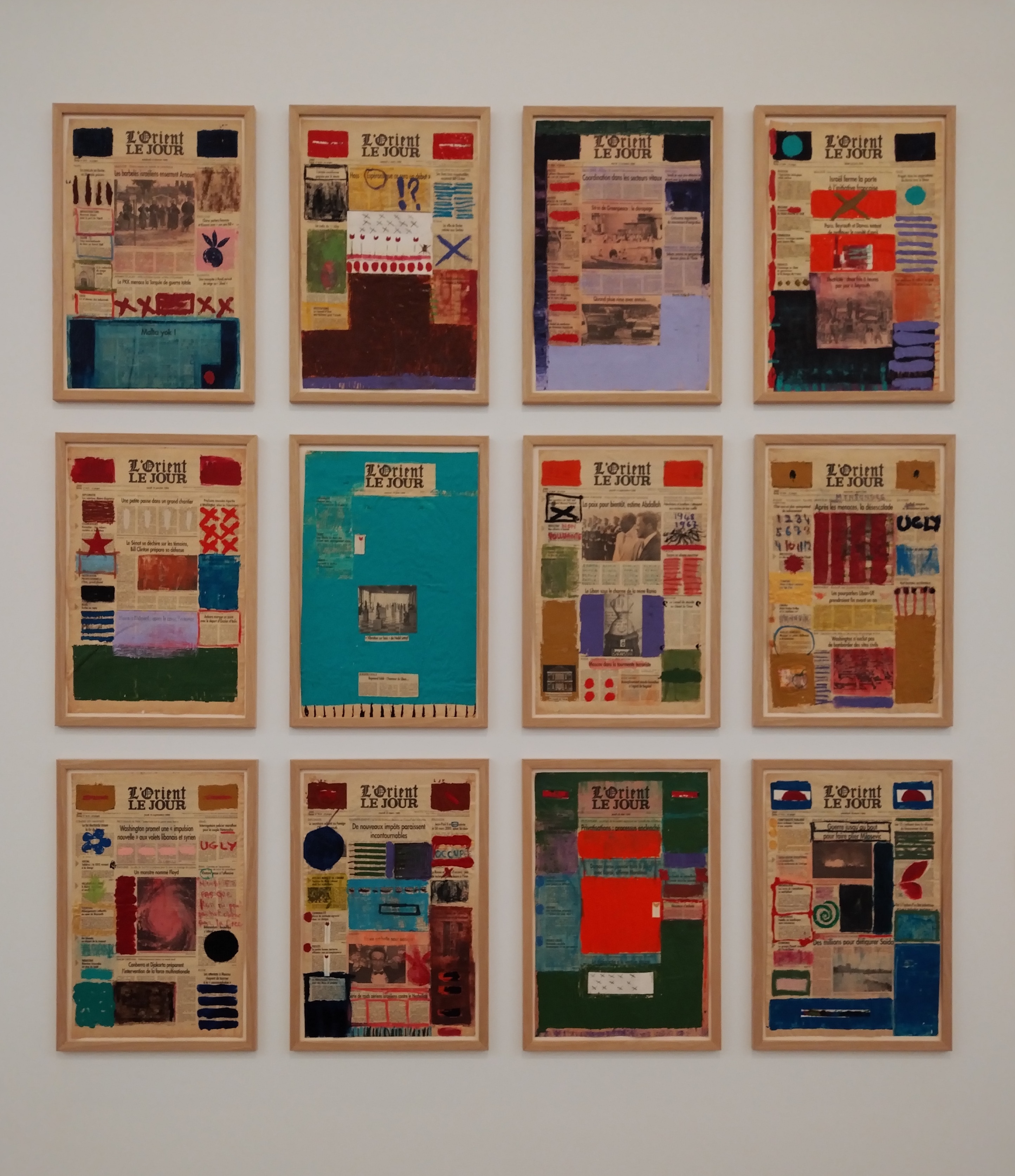 12 framed front pages of a newspaper with colourful paint covering some text